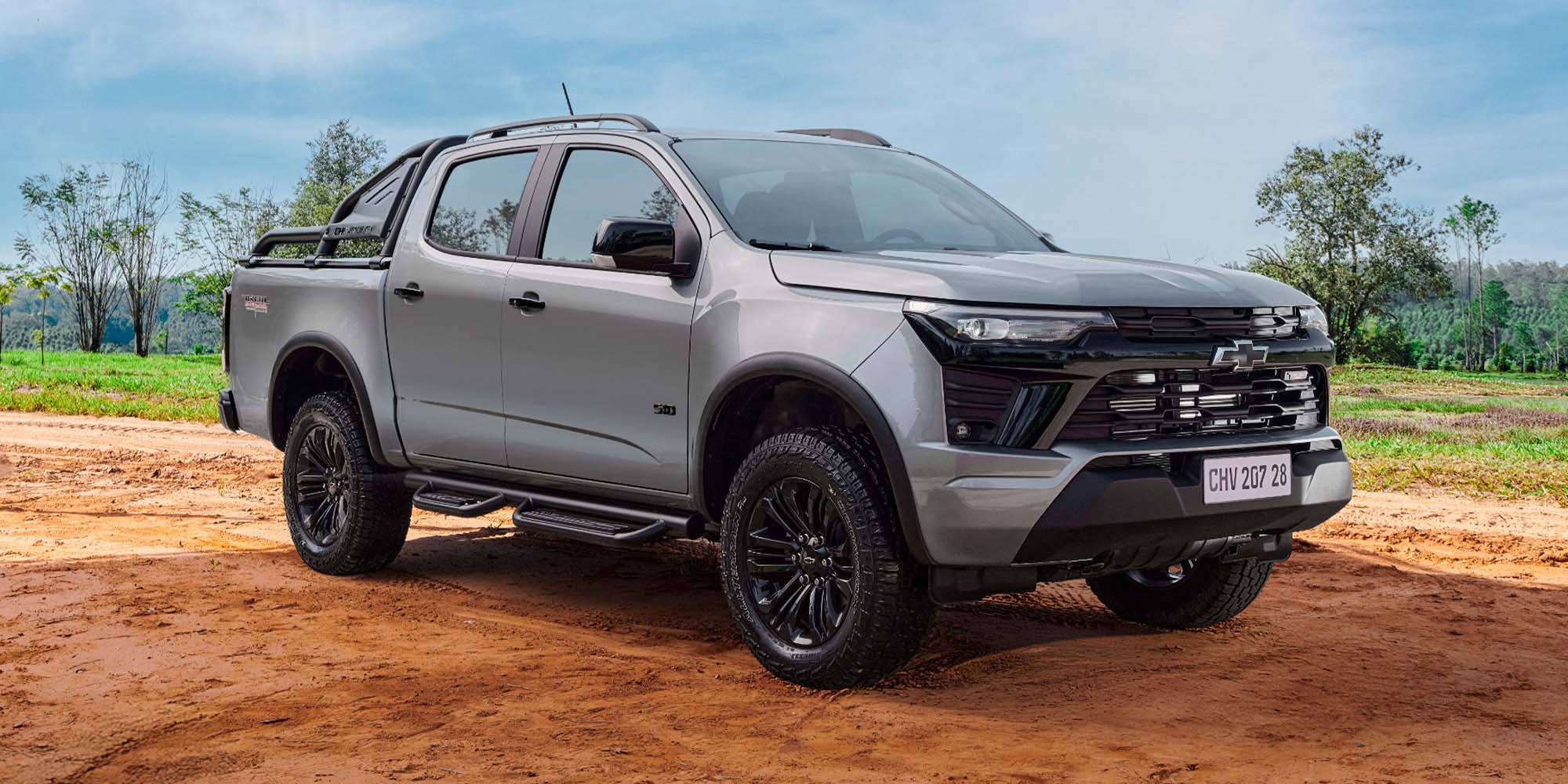 Chevrolet S10 Trail Boss color gris circulando en terreno off-road, destacando su suspensión recalibrada y capacidad para enfrentar caminos difíciles.